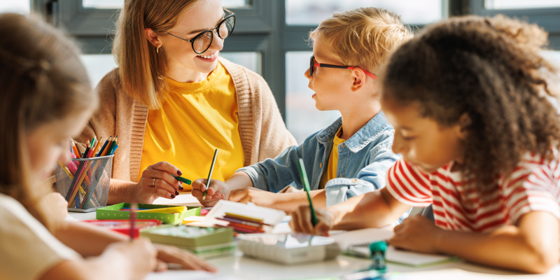 Teacher helping children with schoolwork